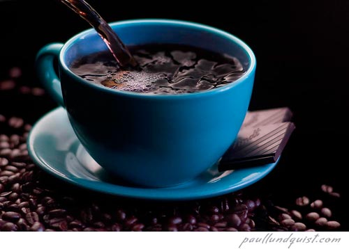 Blue coffee cup on coffee beans with chocolate.